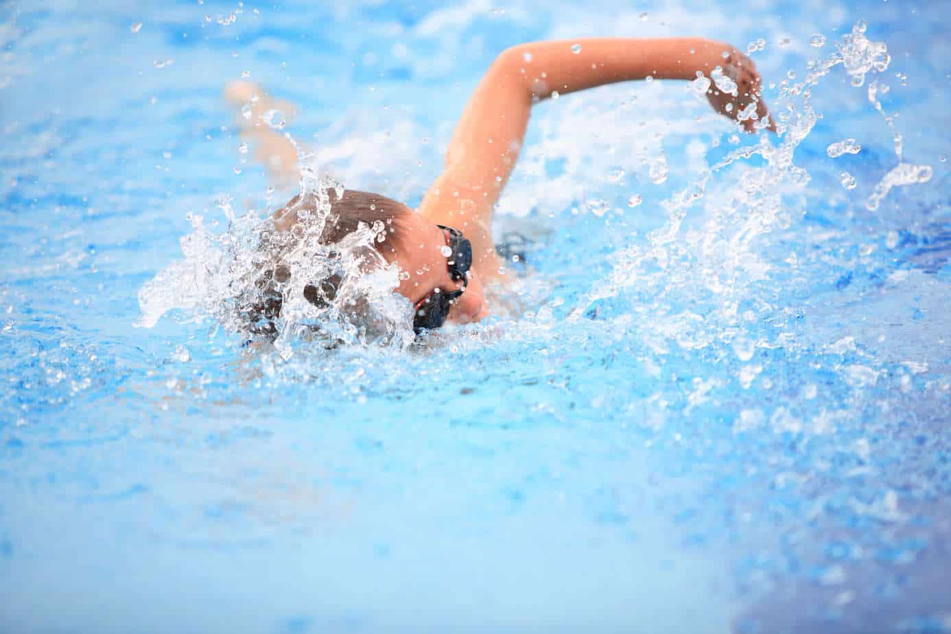 A swimmer in mid-stroke, creating splashes in a Newport Beach pool.