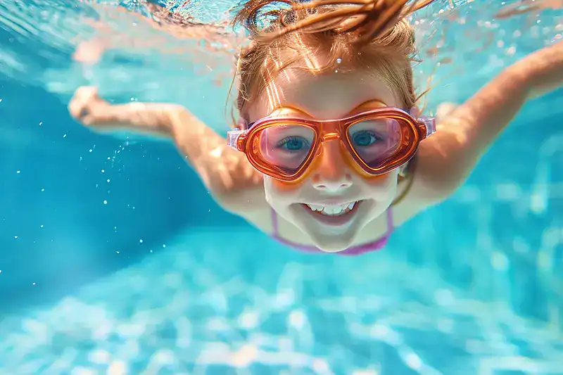 A girl with goggles enjoys an underwater swim